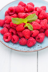 Fresh raspberries in a plate on a  vintage background.