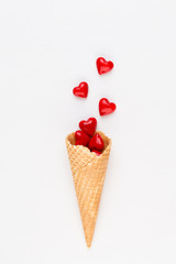 Creative composition for Valentines day with waffle cone, mixed hearts on white background top view. Fashion flat lay.