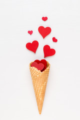 Creative composition for Valentines day with waffle cone, mixed hearts on white background top view. Fashion flat lay.