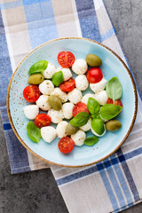 Delicious caprese salad with ripe cherry tomatoes and mini mozzarella cheese balls with fresh basil leaves.