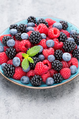 Fresh berry salad on blue dishes. Vintage wooden background.