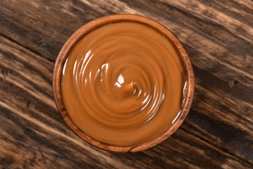 Dulce de leche bowl isolated on wooden background