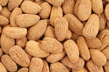 Food background - big shelled roasted salted almonds situated arbitrarily