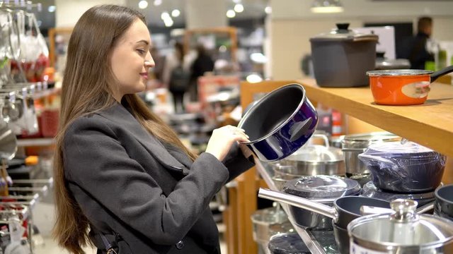 4k shot of a young beautiful woman choosing pan utensil dishes in a store supermarket shop.