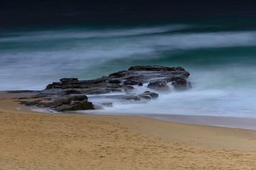 Fototapeta na wymiar waves on the beach over rocks