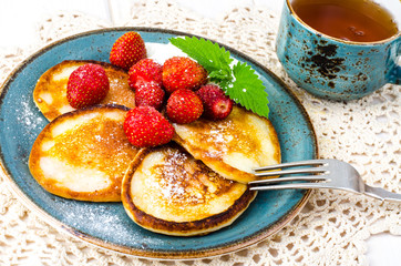 Delicious sweet fried pancakes with sugar and strawberries