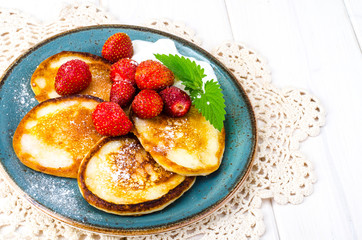 Delicious sweet fried pancakes with sugar and strawberries