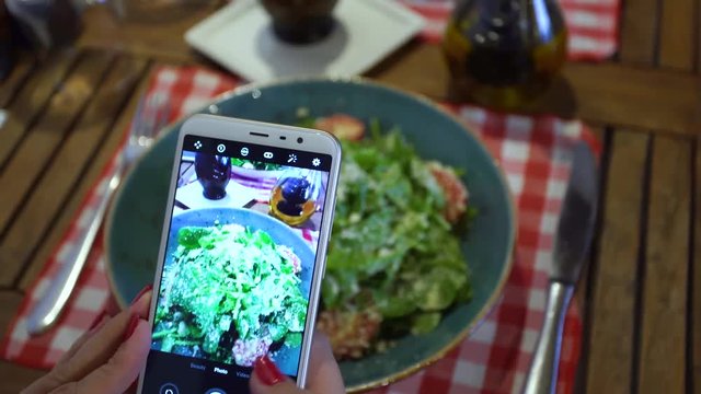 Close-up top view of woman taking photo of her food with digital camera of  cellphone to place pictures at social media resources. Real time 4k video footage.