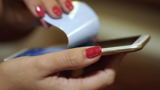 Woman removes protective film from touchscreen of just bought new smartphone. Shallow depth of field. Real time 4k video footage.