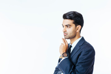Close up portrait of a handsome businessman in suit and tie thinking with hand on mouth and looking to the side, isolated on white studio background