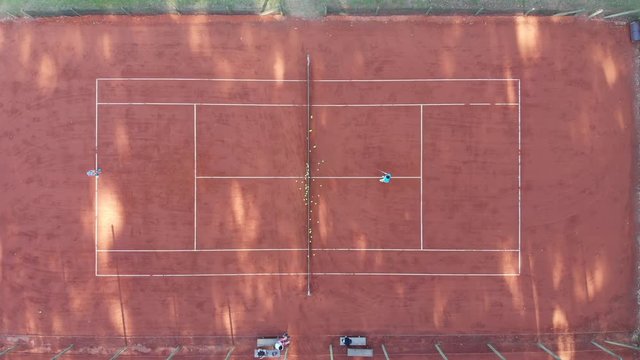 Tennis court seen from above in vertical shot with two players playing a match
