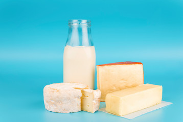 Various fresh dairy products isolated on blue background. Cheese, milk and butter.
