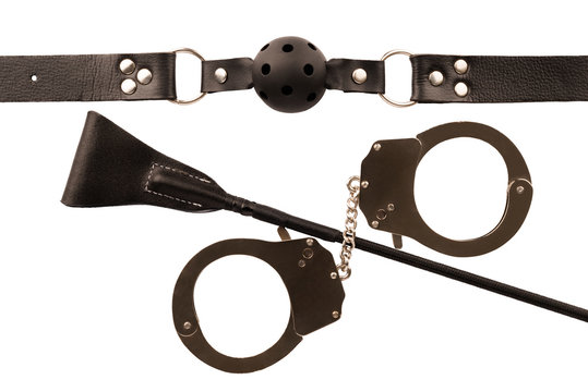 Riding crop, handcuffs and ball gag, isolated on white background. Top view.