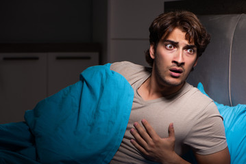 Young man scared in his bed having nightmares
