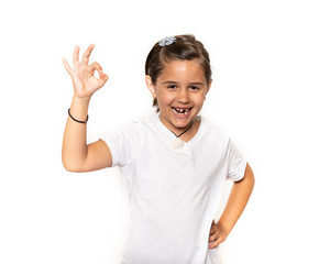 Young primary school aged school girl pointing ok or okay hand sign isolated on a white background.