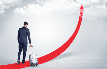 Young businessman with back leaving on the red arrow carpet to the skies with luggage on his hand
