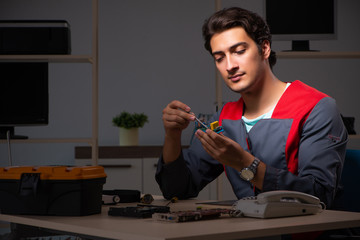 Young handsome repairman repairing computer 
