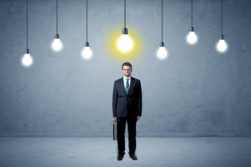Fototapeta premium Handsome businessman in an empty space with bulbs above and uninspired face 