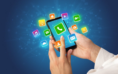 Female hand using smartphone with 3D shiny starlike application icons around
