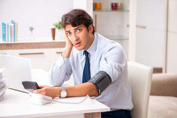 Man under stress measuring his blood pressure