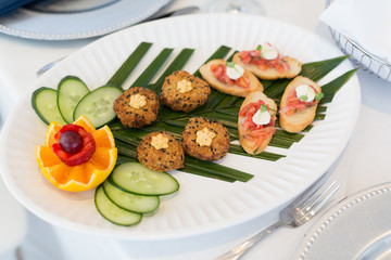 Fototapeta na wymiar Crab cakes and salmon appetizers with fresh cucumber and fruit.