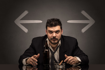 Drunk disappointed man sitting at table with arrows around
