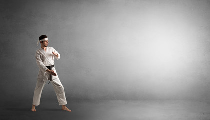 Small karate man fighting in an empty grey copy space