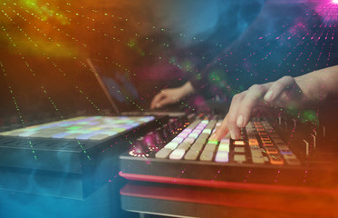 Hand mixing music on midi controller with party club colors around
