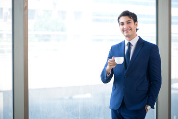 Young handsome businessman standing at the window 