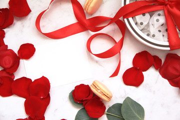 Beautiful bright red rose petals on white background. Happy Valentine's day. White box with red bow. Gift