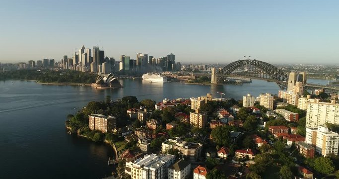 Waterfront of Sydney city CBD with Harbour bridge across Sydney harbour in aerial descending view behind Kirribilli residential suburb on Lower North Shore.
