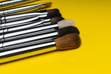 Fototapeta premium professional set of red makeup brushes on yellow background with copy space close up