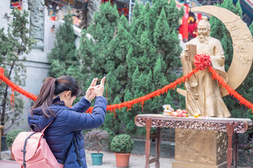 Fototapeta na wymiar Young woman ties red rope and pray at Yue Lao (God of marriage) in Wong Tai Sin Temple, is well known for love and marriage prayers answered. landmark and popular for tourist attractions in Hong Kong