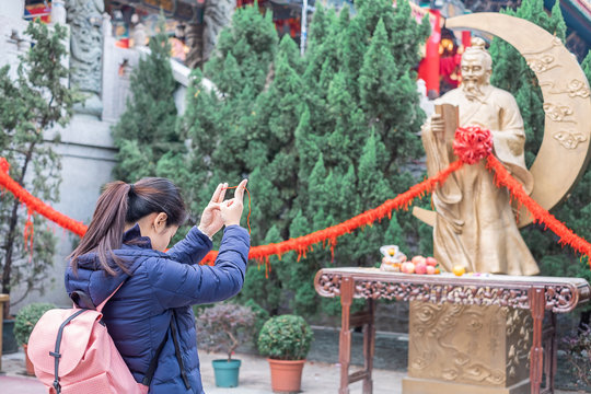 Young woman ties red rope and pray at Yue Lao (God of marriage) in Wong Tai Sin Temple, is well known for love and marriage prayers answered. landmark and popular for tourist attractions in Hong Kong
