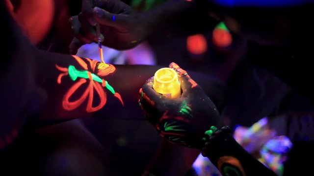 The artist draws fluorescent paints on the guy's hand before the party in the club. Close up. The famous full moon party on Koh pangan island 1920x1080