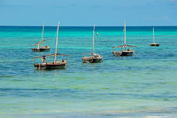 Wooden sailboats (dhows) on the clear turquoise water of Zanzibar island