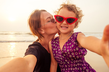Happy stylishly mother and daughter taking selfie at sandy beach on a sunset.mothers Day.little...