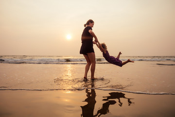 Fototapeta premium happy family at the beach. mother hugging child daughter and fly tourism with children