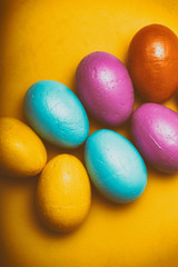 Easter eggs of different colors on a yellow background.