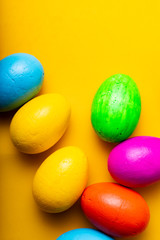 Easter eggs of different colors on a yellow background.