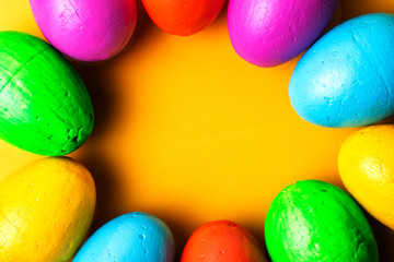 Easter eggs of different colors on a yellow background.