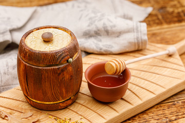 Barrel with honey inside the pollen and spoon on a wooden table. Rustic still life.