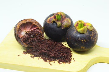 mangosteen peel and mangosteen peel powder on top of a wooden bowl