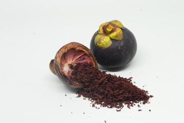 mangosteen peel and mangosteen peel powder on top of a wooden bowl