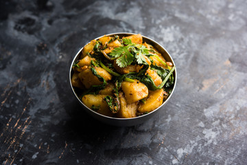 Aloo Palak sabzi - Potato cooked with spinach with added spices. a healthy Indian main course recipe. Served in a bowl, selective focus