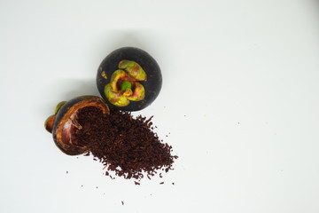 mangosteen peel and mangosteen peel powder on top of a wooden bowl © Fatrin