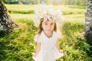 Fototapeta na wymiar happy young girl with a wreath of flowers on her head Caucasian appearance smiling in the summer outdoors
