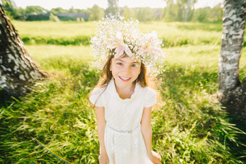 Fototapeta na wymiar happy young girl with a wreath of flowers on her head Caucasian appearance smiling in the summer outdoors
