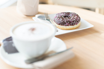 Chocolate donut with a cup of coffee on table