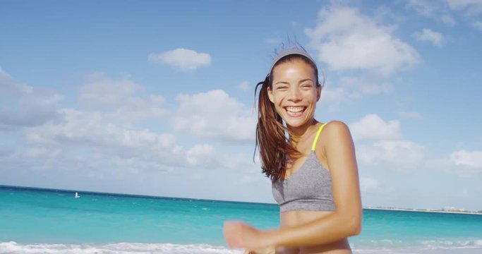 Happy sporty woman running having fun cheerful on beach vacation. Cheerful funny mixed race girl on Caribbean beach. RED EPIC SLOW MOTION